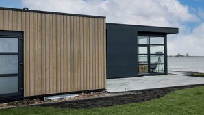 A modern building with a wooden facade and a glass section. - Modern Holiday Home With a Deco Fireplace (Enkhuizen)
