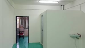 A room with a green floor, white walls, a white sink, and a door leading to another room. - LZ Hostel (Bangkok)