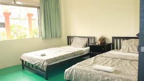 A room with two single beds, a window with a curtain, and a green floor. - LZ Hostel (Bangkok)