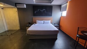 A hotel room with a large bed, a nightstand, a wall-mounted TV, and a chair. - 4Play Motel (El Marques)