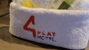 A bathroom with a white towel rack holding towels, a sink, and a mirror. - 4Play Motel (El Marques)