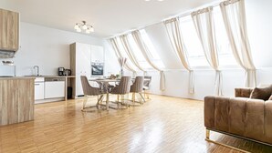 Et moderne køkken med spiseplads, trægulv og en sofa.