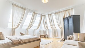 Et soveværelse med seng, garderobe, stol og sofa.