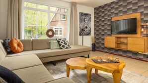 A modern living room with a sofa, a TV, and a wooden coffee table. - Holiday Home in Bad Bentheim Near Dutch Border (Bad Bentheim)