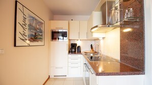 Una cocina moderna con armarios blancos, un lavamanos de acero inoxidable y una encimera de granito.