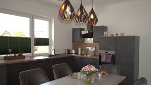 A modern kitchen with dark cabinetry, a central island, and pendant lighting. - Holiday Apartment Busch (Bad Sachsa)