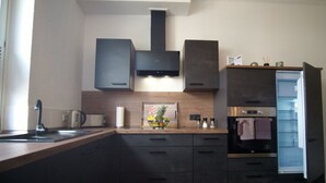 A modern kitchen with dark cabinetry, a built-in oven, a microwave, and a stainless steel sink. - Holiday Apartment Busch (Bad Sachsa)