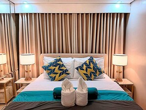 A hotel room with a bed, two nightstands, lamps, a headboard, and curtains.