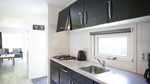 Eine moderne Küche mit dunklen Schränken, einer Edelstahl-Spüle und einem Fenster über der Arbeitsplatte.
