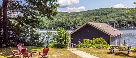 A lakeside cabin with a dock, surrounded by greenery and a clear view of the lake.