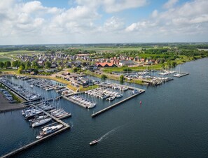 An aerial view of a marina with numerous boats docked, surrounded by residential buildings and greenery. - Villa by Lake Veerse Meer With Sauna and Terrace (Wolphaartsdijk)