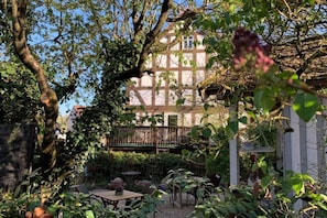Una casa tradicional de entramado de madera con un patio jardín, rodeada de exuberante vegetación y árboles.