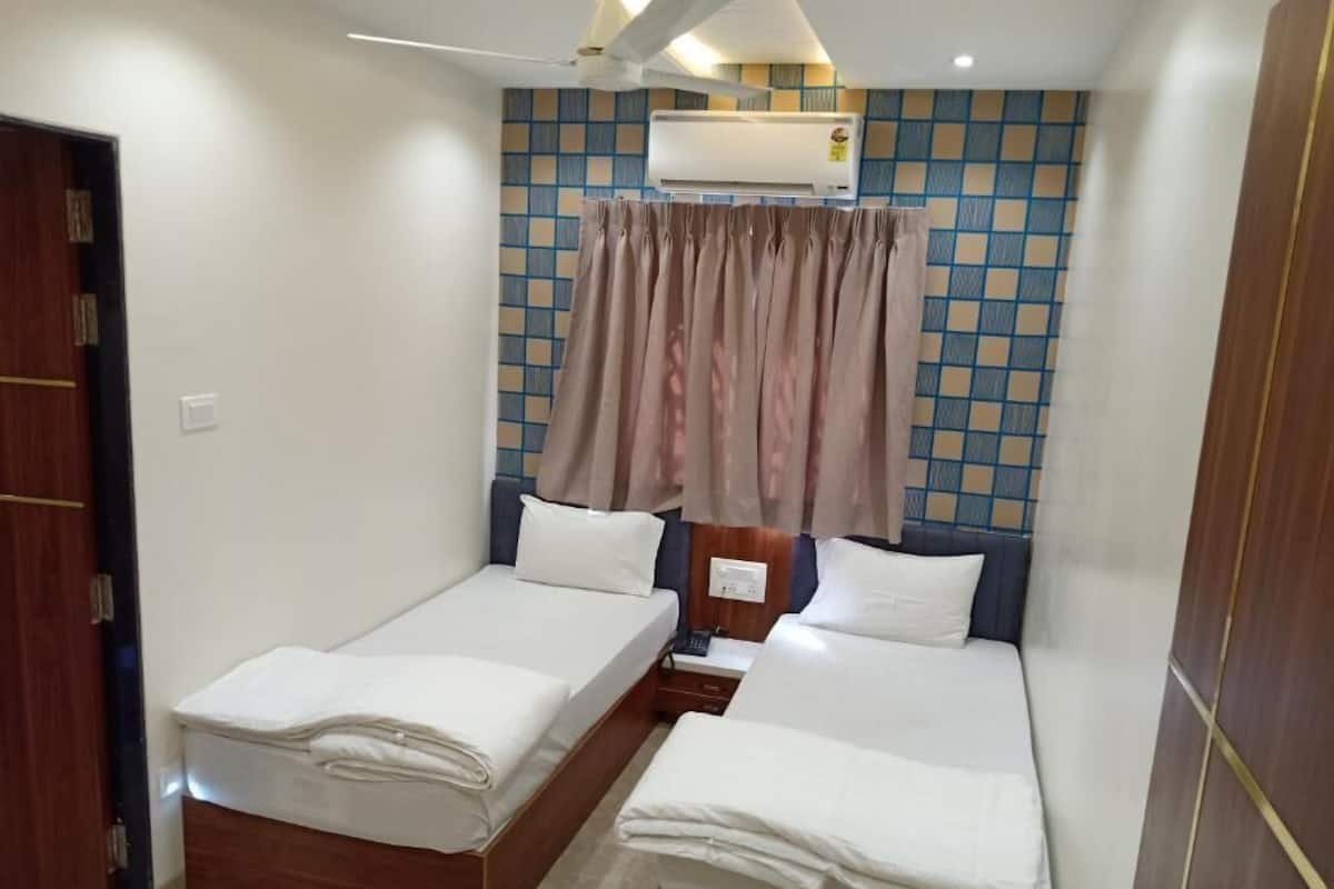 Habitación de hotel con dos camas, un armario, un equipo de aire acondicionado y una cortina.