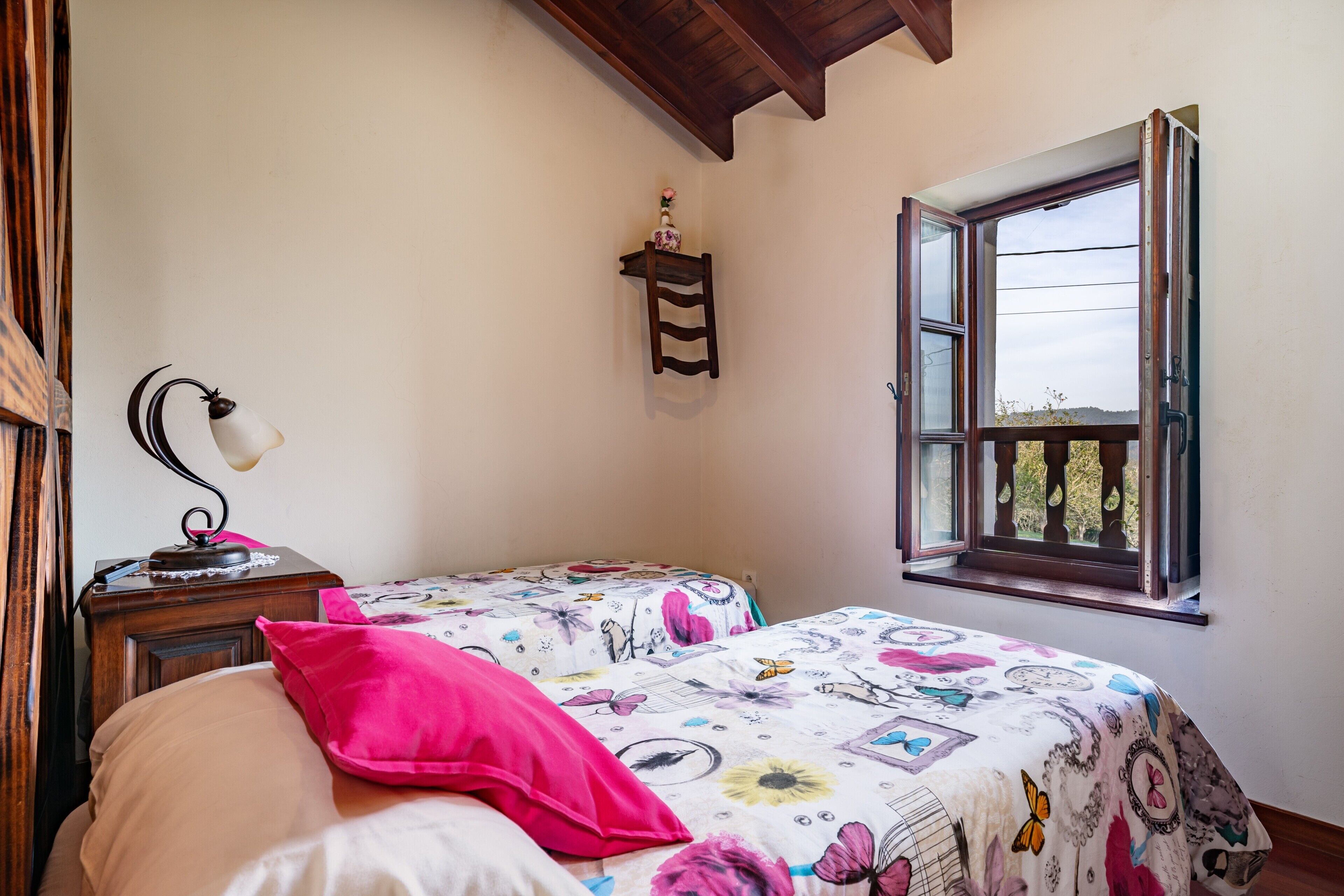 Un dormitorio con dos camas, una ventana, una mesita de noche y un estante en la pared.