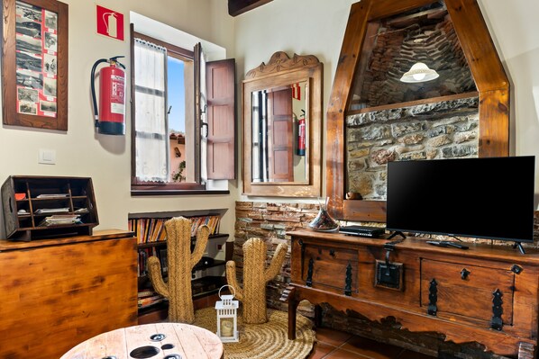 A cozy room with a stone fireplace, wooden furniture, a television, and a cactus decoration.