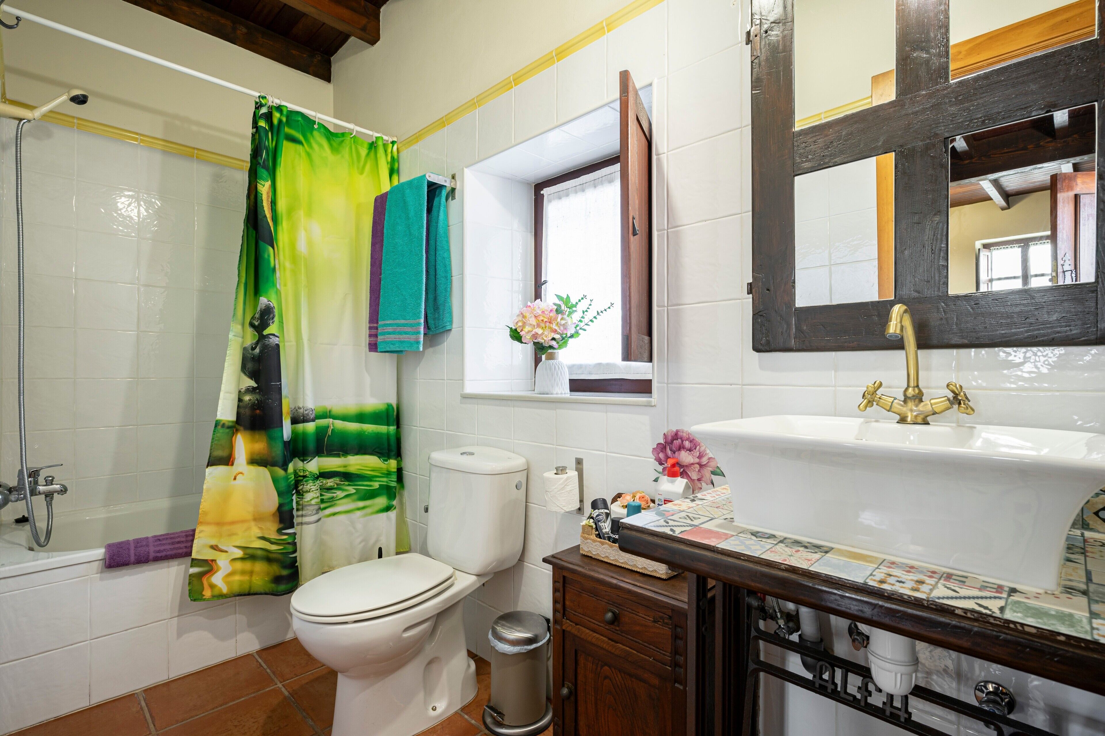 A bathroom with a toilet, sink, shower, and a mirror.