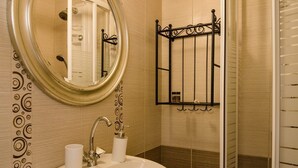 A bathroom with a sink, mirror, and shower area.