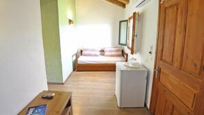 Une petite pièce comprenant un lit, un bureau, une armoire et un plafond en bois.