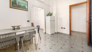 A dining area with a table, chairs, and a painting on the wall. - Arbus Aventino Centrale Holiday Home with Private Terrace and Air Conditioning (Arbus)