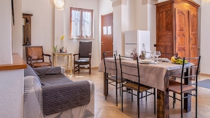 Ein Essbereich mit einem Tisch für vier Personen, einem Holzschrank und einer Couch.