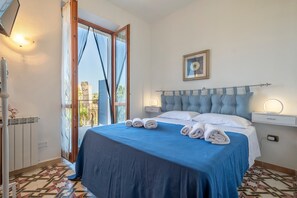 Une chambre à coucher avec un lit, une fenêtre avec des rideaux, une table de chevet avec une lampe et un tableau accroché au mur.