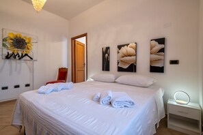 A neatly made bed with towels, a bedside table with a lamp, and wall art.