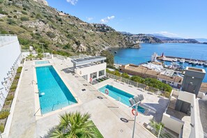 A rooftop pool area with two swimming pools, a lifeguard tower, and a view of the sea and hills. - Apartment 'Icon Marina D' with Sea View, Wi-Fi and Air Conditioning (La Herradura)