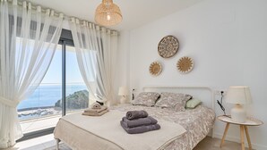 Una camera da letto con un letto grande, vista sul mare e decorazioni alle pareti.