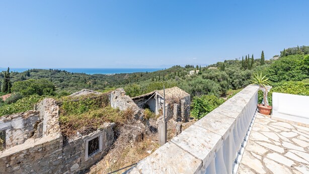 A stone wall with ruins and a potted plant, overlooking a lush landscape and distant sea. - Holiday Home 'Priest's Traditional Mansion' with Sea View, Shared Terrace and Wi-Fi (Corfu)