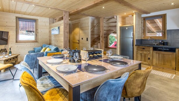 Un intérieur en bois comprenant une table à manger pour quatre personnes, un canapé et un coin cuisine.