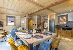 Ein Holzinterieur mit Esstisch für vier Personen, einer Couch und einer Küchenzeile.