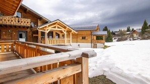 Un chalet en bois doté d’un balcon, d’un porche abrité et d’un terrain enneigé.