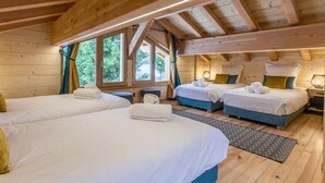 Une cabane en bois avec trois lits, une fenêtre avec des rideaux et une table de chevet avec une lampe.