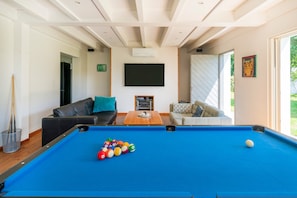 A pool table with balls, a sofa, a television, and a door leading to a balcony. - Villa 'Charming Landes House with Private Pool, Wi-Fi and Air Conditioning' (Labenne)