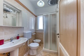 Een badkamer met een wastafel, toilet, bidet en een douchecabine.