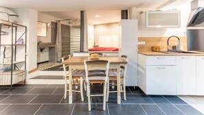 Een moderne keuken met een eethoek, witte kasten en een betegelde vloer.