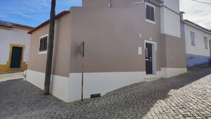 A two-story building with a flat roof, a visible door, and a small window.