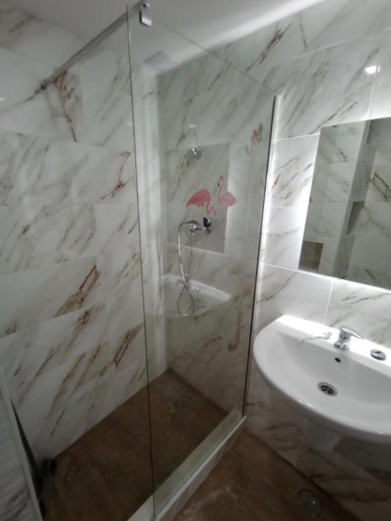 Une salle de bain avec une douche à parois de verre, un lavabo et des murs en marbre.