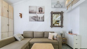 Ein Wohnzimmer mit Sofa, Couchtisch, Schrank und Wandbildern.