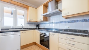 Een moderne keuken met witte kasten, een vaatwasser, een oven en een aanrecht met een behangetje.