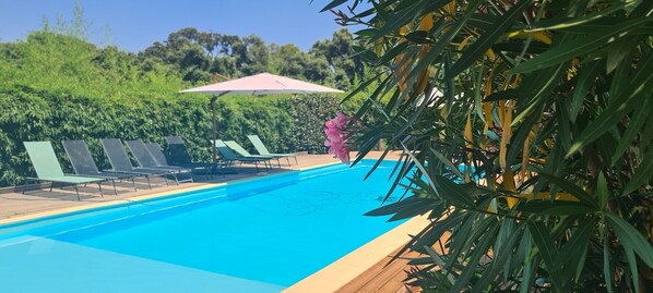 A swimming pool with lounge chairs and an umbrella.