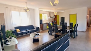 A modern living room with a sofa, coffee table, and dining area with chairs. - Villa 'A Suara' with Mountain View, Private Pool and Private Terrace (Canale-di-Verde)