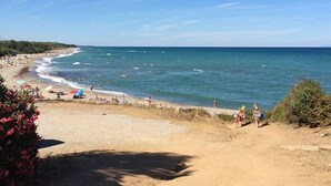 A beach with clear blue water, sandy shore, and some vegetation. - Villa 'Via Ferrata' with Mountain View, Private Pool and Private Terrace (Canale-di-Verde)