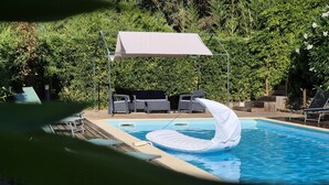 A swimming pool with a floating mattress, lounge chairs, and a covered seating area. - Villa 'Via Ferrata' with Mountain View, Private Pool and Private Terrace (Canale-di-Verde)