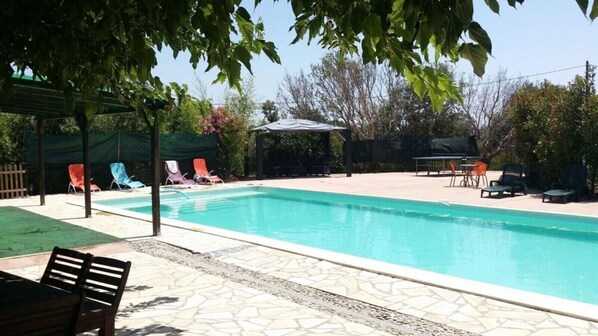 Une piscine avec des chaises longues et une pergola.