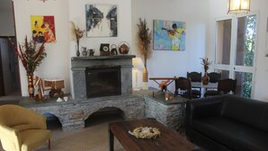 Ein Wohnzimmer mit Kamin aus Stein, einem schwarzen Sofa, einem Holztisch und einem gelben Sessel.