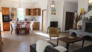 Ein modernes Wohnzimmer mit einer Couch, einem Couchtisch und einem Kamin. Es gibt einen Essbereich mit Tisch und Stühlen.