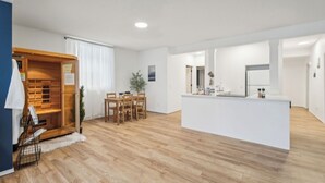A modern kitchen with a central island, wooden dining table, and chairs.