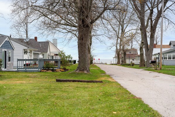 A residential street with houses, a sidewalk, and a large tree.