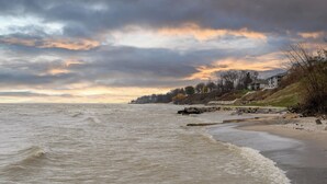 Een kustlandschap met een strand, golven en een gebouw met meerdere verdiepingen.